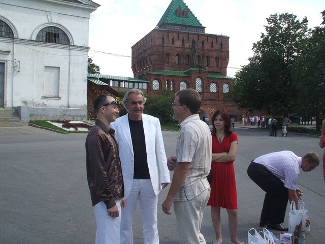 Roel van Duijn in een wit pak, in gesprek met een groep mensen voor de rode toren van het kremlin van Nizjni Novgorod